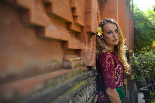 a woman leaning against a wall with a flower in her hair